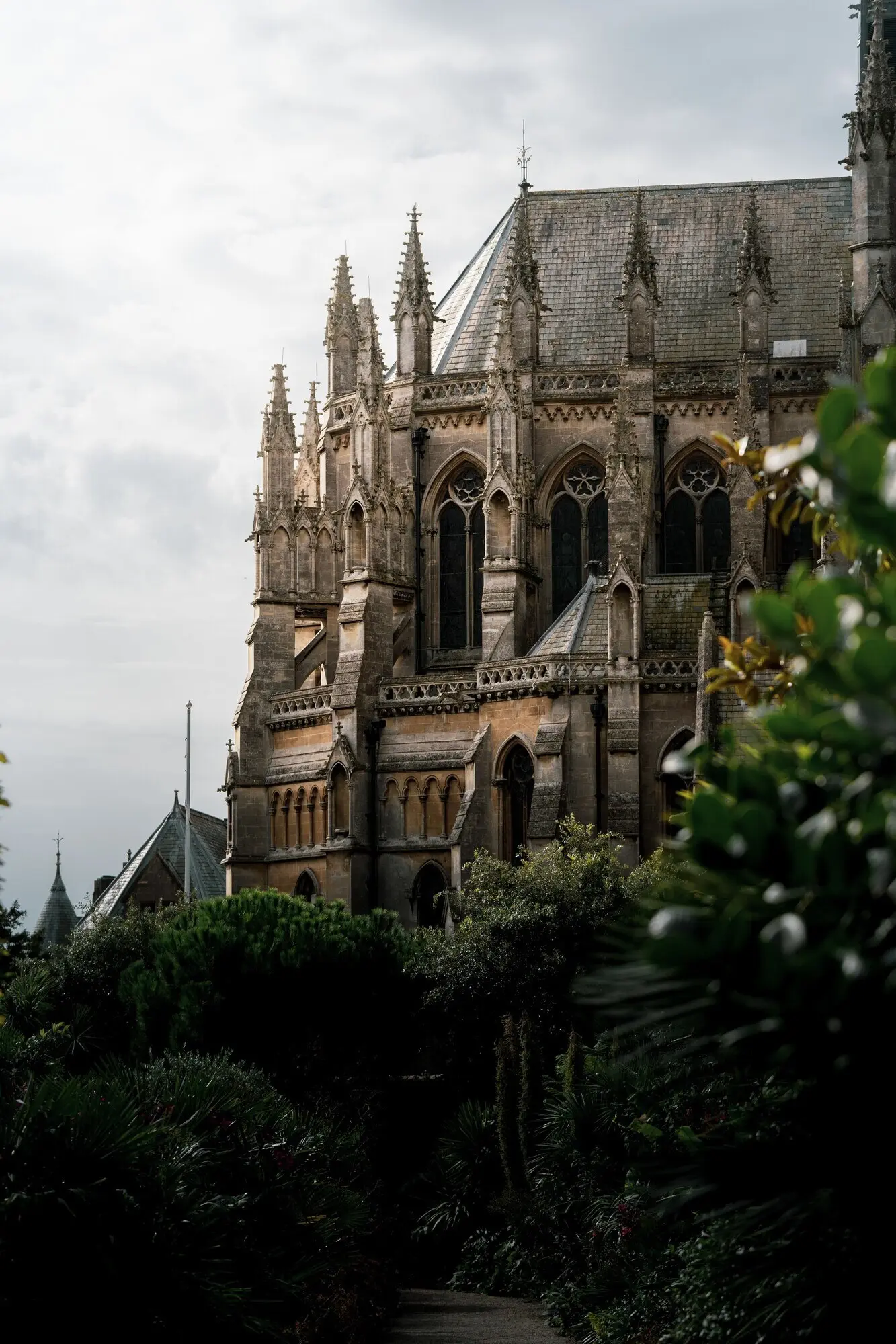 Vertikales Foto von Arundel Castle und der Kathedrale, umgeben von schönem Laub, bei Tageslicht.