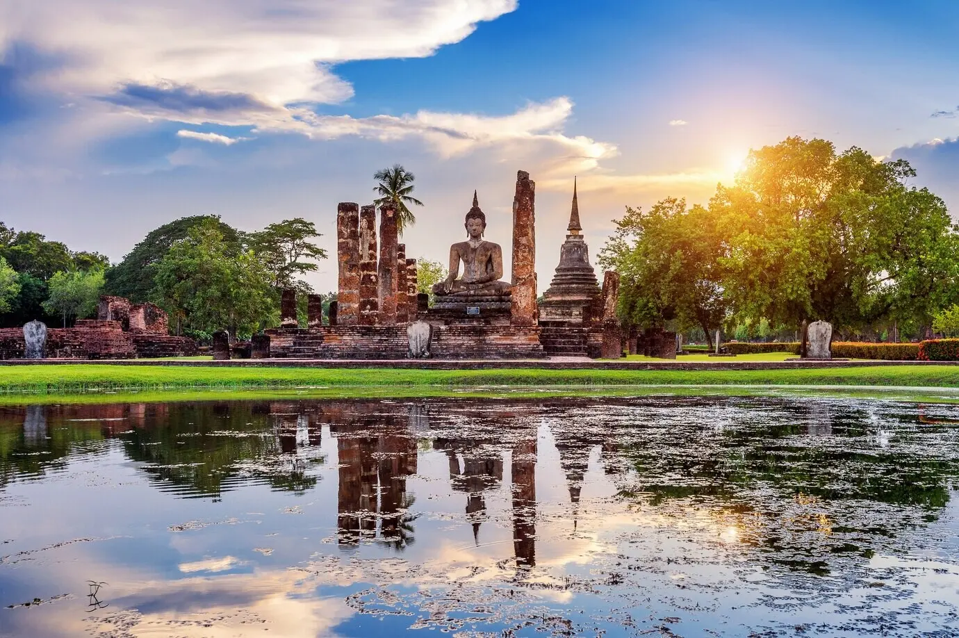Buddha-Statue und der Tempel Wat Mahathat auf dem Gelände des Historischen Parks Sukhothai.